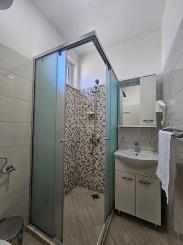 Un baño con ducha de cristal y lavabo. en Casa ROBI - Apartments, en Ulcinj