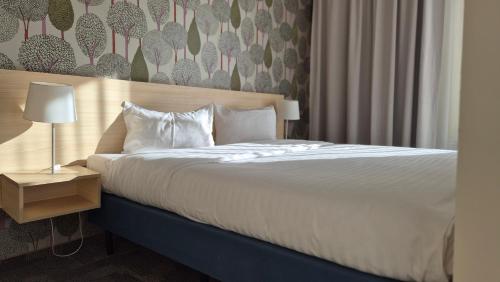 Una cama con sábanas blancas y almohadas en una habitación. en Golden Tulip Międzyzdroje Residence, en Międzyzdroje