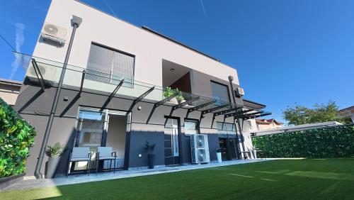 ein weißes Haus mit einem Rasen davor in der Unterkunft Royal Rest Apartments Karlovac in Karlovac