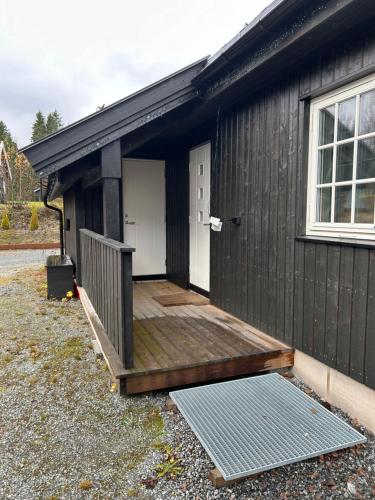 a small black building with a deck and a door at Nordre Hella - cabin with Jacuzzi with 4 bedrooms in Fossby