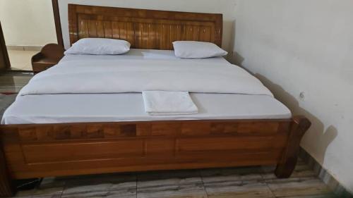 a wooden bed with white sheets and two towels on it at Holliday inn kigali in Kigali