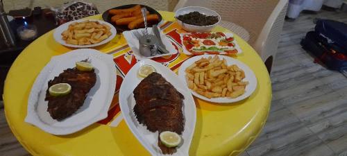 a yellow table with plates of food and french fries at Holliday inn kigali in Kigali
