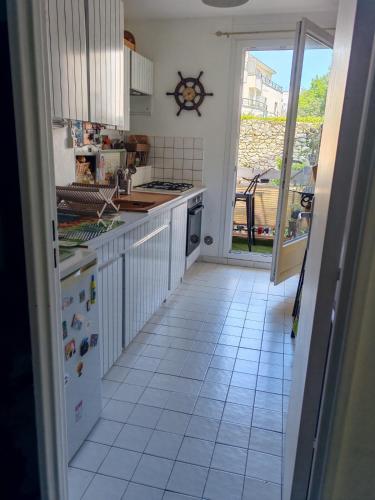 una cucina con pavimento piastrellato bianco e una porta aperta di Cosy Coty a Tours