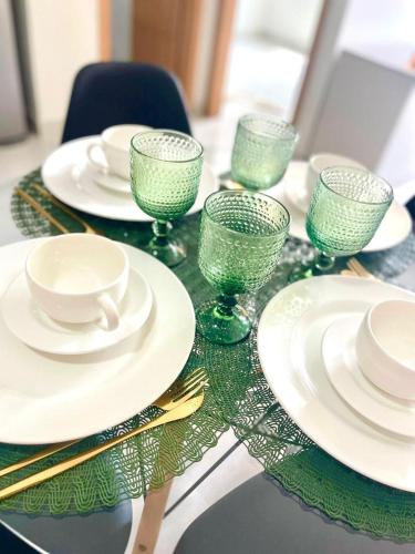 een tafel met groene glazen, borden en eetstokjes bij Apartamento Completo aconchegante- Fácil acesso ao Aeroporto e a COP-30 in Belém