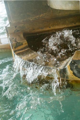 a pool of water pouring out of a boat at Ureshino Motoyu in Ureshino