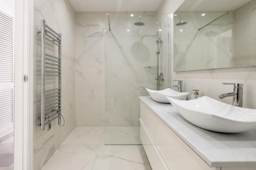 Un baño blanco con dos lavabos y una ducha. en Balcones del Chaparral Peaceful Seafront by Alfresco Stays, en Mijas Costa