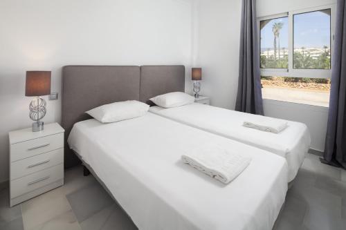 Dos camas blancas en una habitación con ventana. en Balcones del Chaparral Peaceful Seafront by Alfresco Stays, en Mijas Costa