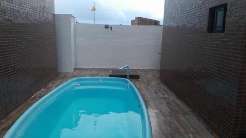 a blue bath tub in a courtyard with a brick wall at Apartamento com dois quartos a 300m da praia in Cabedelo