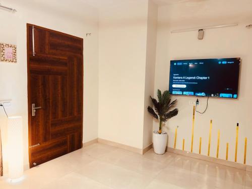 una habitación con TV en una pared con una planta en Bloom Villa, en Mohali