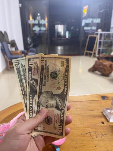 a person holding a dollar bill in front of a table at Moon Hotel & Spa in Mù Cang Chải