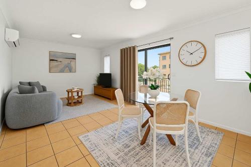 een woonkamer met een tafel, stoelen en een klok bij Beachfront Bliss - At the Heart of It ALL in Townsville