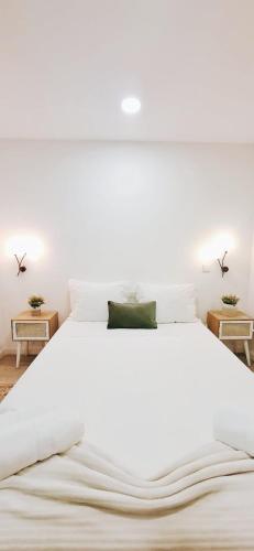 a large white bed in a bedroom with two tables at Casa dos Sequeiras Port Rosé in Vila Nova de Gaia