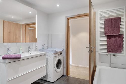 baño blanco con lavadora y lavamanos en Stockerhof, en Elzach