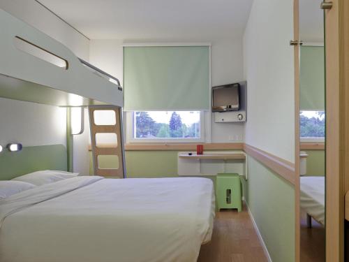 a hospital room with a bed and a tv at ibis budget Genève Petit-Lancy in Geneva