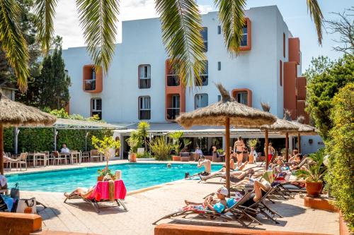 a group of people sitting in lawn chairs by a swimming pool at Hotel Aquarius in Canet-en-Roussillon