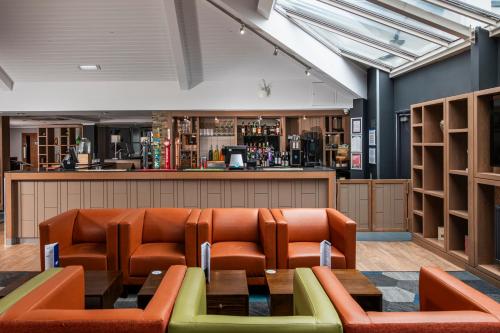 a waiting room with orange chairs and a bar at Holiday Inn Express Edinburgh Airport by IHG in Ingliston