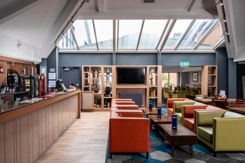 a restaurant with tables and chairs and a bar at Holiday Inn Express Edinburgh Airport by IHG in Ingliston