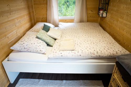 Una cama en una casa pequeña con almohadas. en Maringotka Votavka, en Borovy