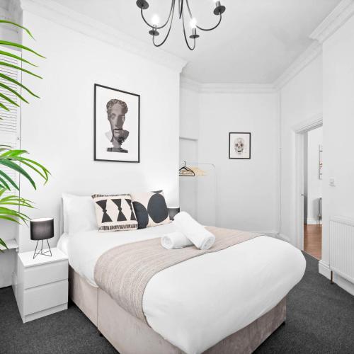 a white bedroom with a large bed and a chandelier at Modern Apartment - Pet Friendly - Fast Wi-Fi - Netflix - Wolverhampton 7PC in Wolverhampton