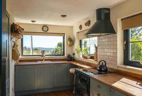 Il comprend une cuisine équipée d'une cuisinière, d'une fenêtre et d'un évier. dans l'établissement Luxury Skye Cottage Hot Tub & BBQ Lodge, à Lonmore