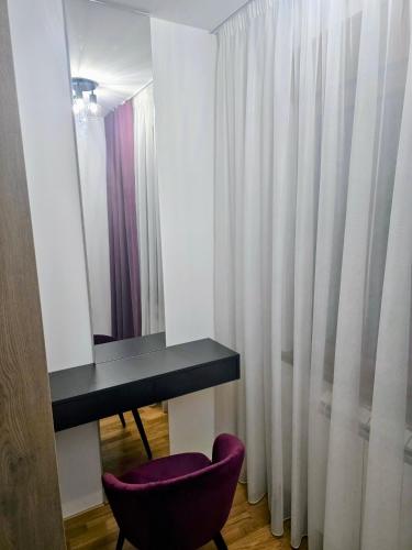 a room with a desk and a purple chair and a mirror at AKI lux apartman in Čačak