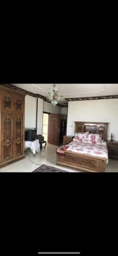a bedroom with a large bed and a chandelier at Allam's Villa - Families only in Borg el Arab