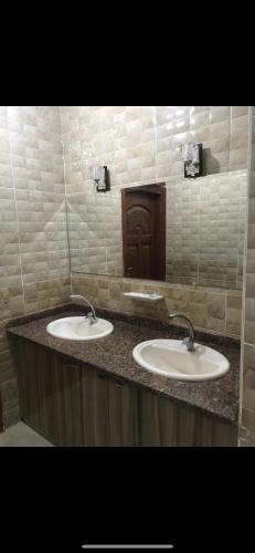 a bathroom with two sinks and a counter with two mirrors at Allam's Villa - Families only in Borg el Arab