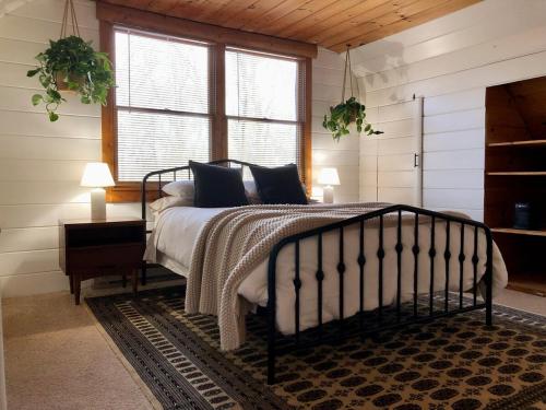 a bedroom with a bed in a room with windows at Modern Mountaintop Cabin with a gorgeous view in Great Cacapon