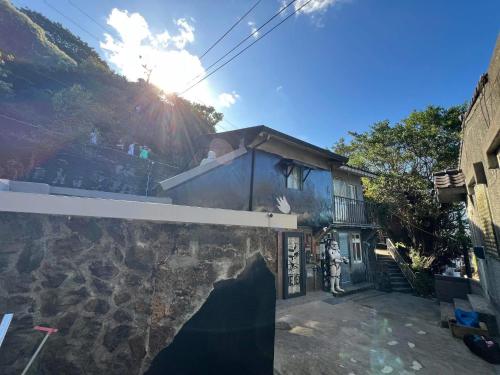 a house with the sun shining behind a wall at 九份玩具屋 in Ruifang