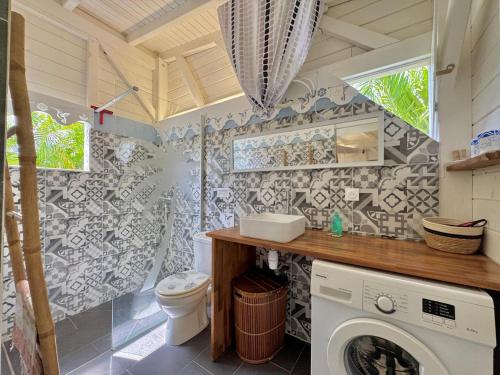 ein Badezimmer mit Toilette sowie Waschmaschine und Trockner in der Unterkunft Ti kaz a Max in Saint-François