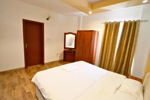 a bedroom with a white bed and a mirror at Muscat-Seeb 1BHK comfort apartment in Seeb