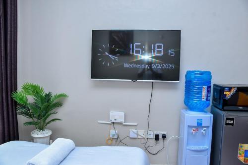 een kamer met een tv aan de muur en een bed bij Mex Homes Studio Apartment in Nairobi