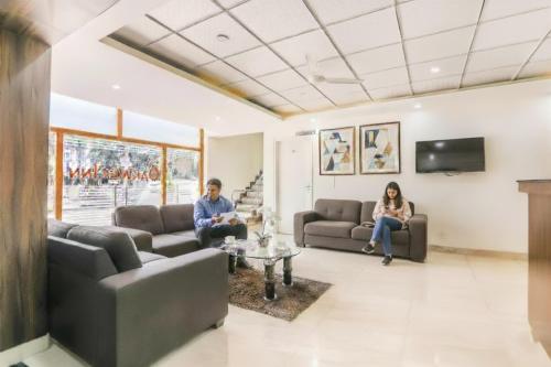 two people sitting on couches in a living room at FabHotel Oakwey Inn - Indiranagar in Bengaluru