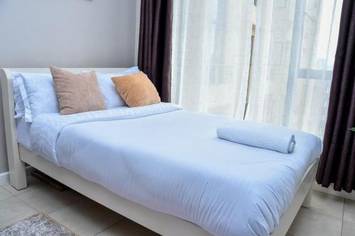 een bed met kussens in een kamer met een raam bij Mex Homes Studio Apartment in Nairobi