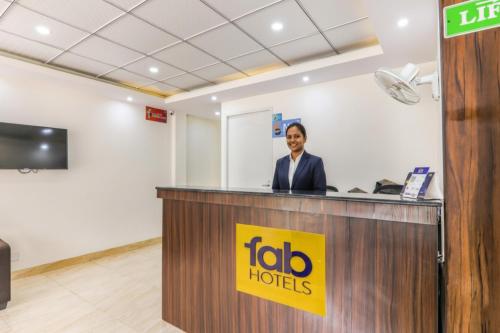 a woman is standing at a reception desk at FabHotel Oakwey Inn - Indiranagar in Bengaluru