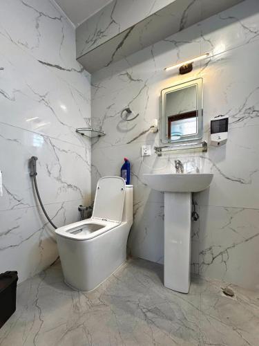 a white bathroom with a toilet and a sink at Bliss View Apartments Nepal in Pātan