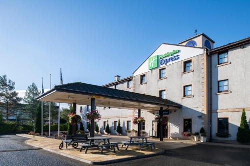 a group of picnic tables in front of a hotel at Holiday Inn Express Perth by IHG in Perth