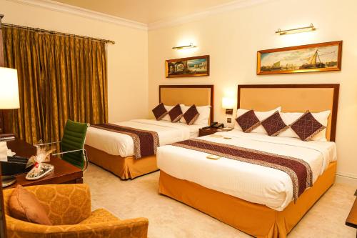 a hotel room with two beds and a chair at Royal Park Residence Hotel in Dhaka
