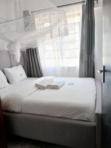 a bed with two books on it with a window at Happy Homes BnB in Kisumu