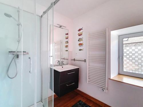 ein Badezimmer mit Waschbecken und Glasdusche in der Unterkunft La petite Mainerie in Jobourg