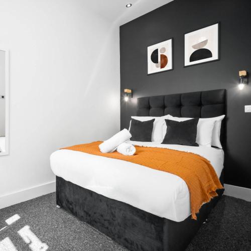 a bedroom with a large bed with an orange blanket at Cozy Apartment - On street parking - Rowley Regis 49AG in Halesowen