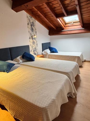 two beds in a room with wooden ceilings at Casa Criseva II in Avín