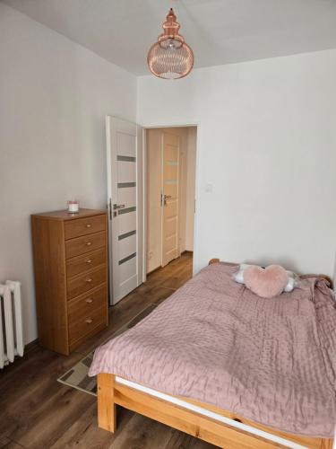 ein Schlafzimmer mit einem Bett mit zwei rosa Kissen und einer Kommode in der Unterkunft Apartamenty EverySky Karkonoska 54/7 in Bierutowice