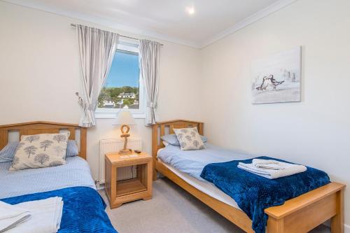 a bedroom with two beds and a window at Pebble Reach in Amroth