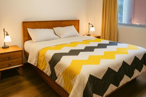 a bedroom with a bed with a yellow and white comforter at San Diego Suites Confort, Vista & Estacionamiento en Cuenca in Cuenca