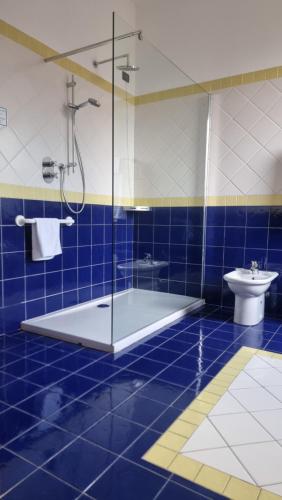 a blue tiled bathroom with a shower and a toilet at Hotel De La Ville in Bereguardo