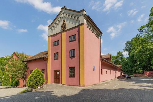 a pink and yellow building with a tree at Hotel STARÝ PIVOVAR in Prague