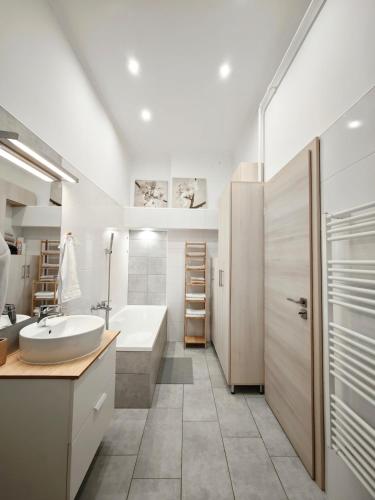 a bathroom with a sink and a tub and a toilet at Vibe City Apartment in Kecskemét