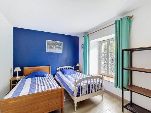 two beds in a bedroom with a blue wall at La Mainerie in Jobourg
