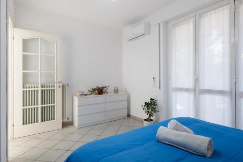 a white bedroom with a blue bed and a cabinet at Casa Martina in San Fermo della Battaglia